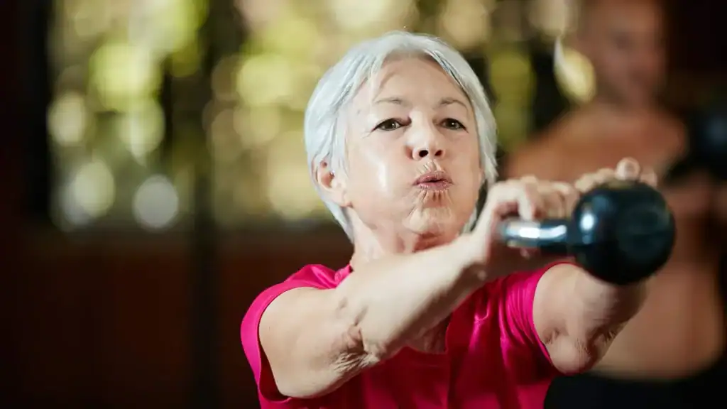 Older woman doing weight training England to help her strength and longevity 