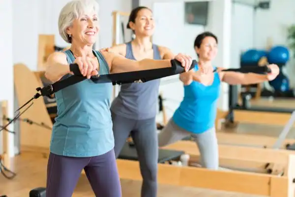 Toning Arms After 60: Empowering Womens Fitness Through Effective Weight Training 2 older woman doing weight training England and resistance in the gym to tone upper arms