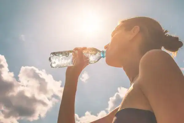 Hydration: The Secret Ingredient for a Toned Stomach and Enhanced Fitness 3 Image of woman drinking water to hydrate England after run.