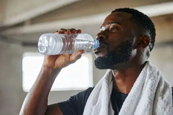 Image of man drinking water to improve hydration England after work out.